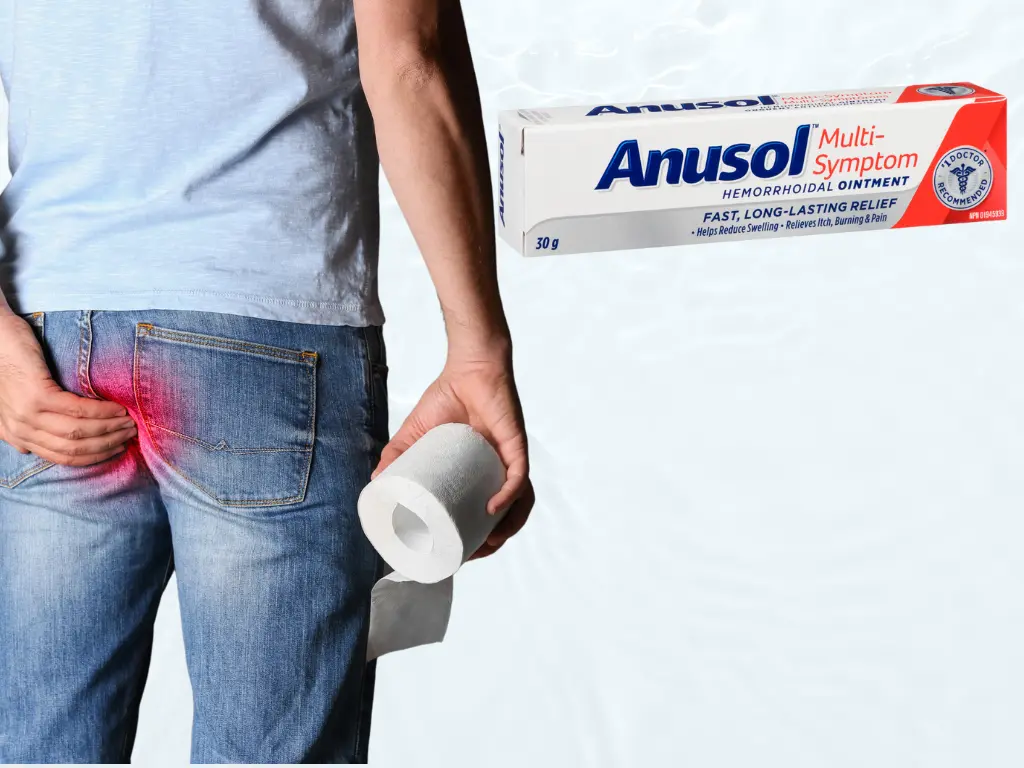 Man standing and holding toilet paper in one hand and his bottom with the other hend and a box of anusol cream for hemorrhoids