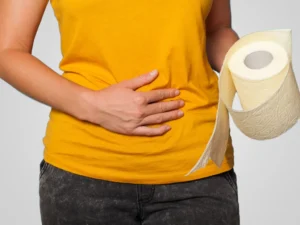 Woman holding a toilet paper and pressing her tummy signalling pain from hemorrhoids