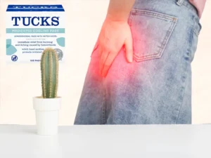 a woman holding her backside signalling pain from hemorrhoids and a cactus next to her, plus a packet of Tucks for hemorrhoids 100 pads